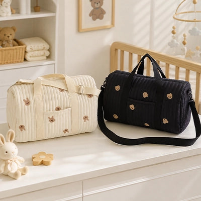 sac a langer ours noir , beige posés sur la table à langer