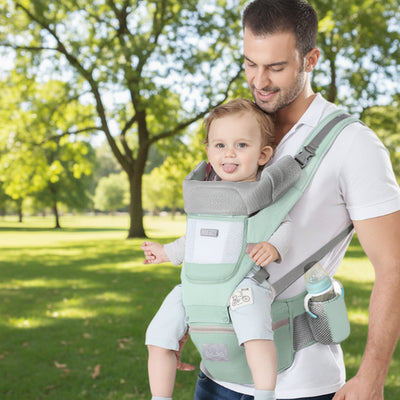 Porte bebe vert, papa porte confortablement bébé assis face vers l'avant