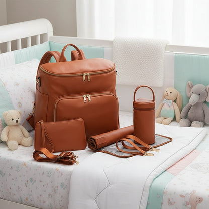 Sac à langer brun avec ses accessoires posé sur le lit de bébé