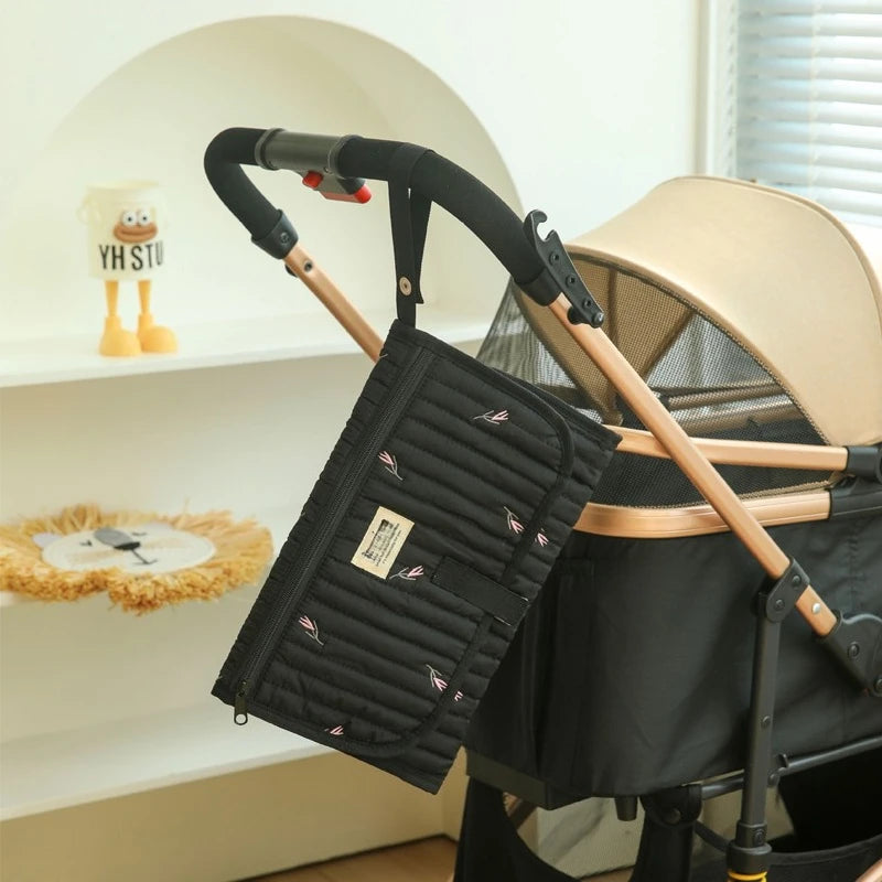 Tapis à langer de voyage  noir accroché sur la poussette