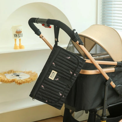 Tapis à langer de voyage  noir accroché sur la poussette