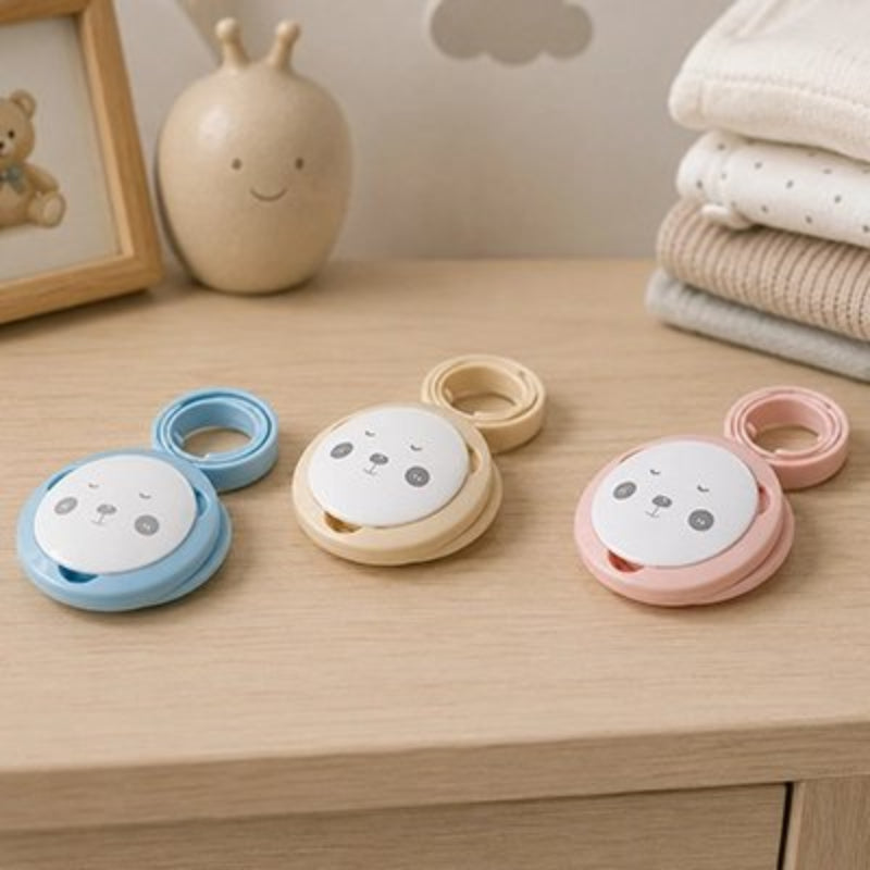 Attache tetine bleu, beige , rose posées sur la table