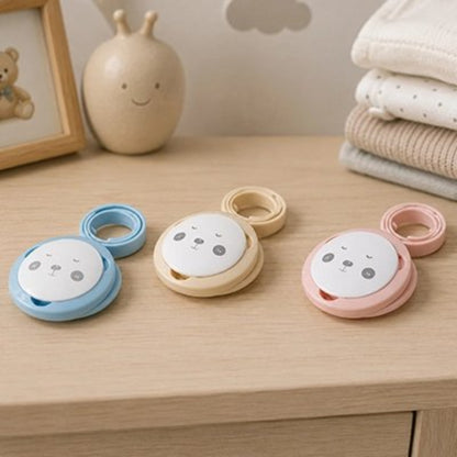 Attache tetine bleu, beige , rose posées sur la table