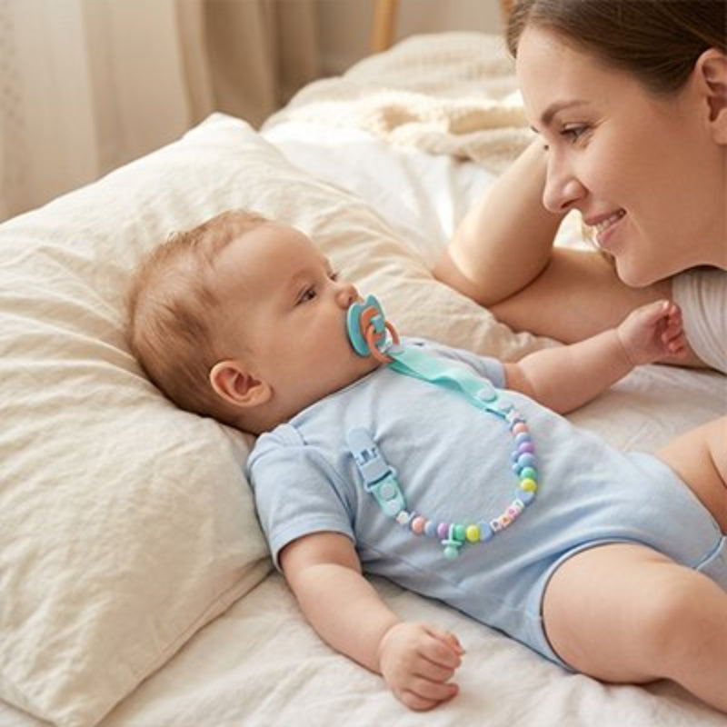 Attache tetine bleu maman qui regarde son enfant couché sur l'oreillé