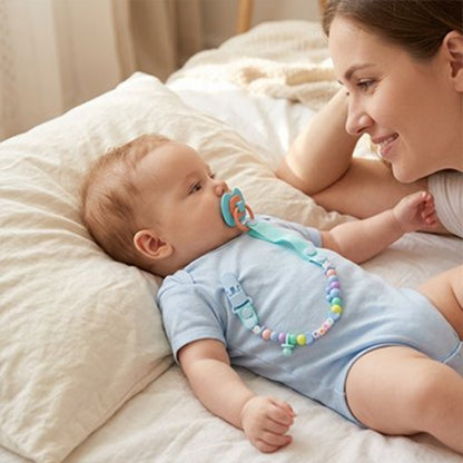 Attache tetine bleu maman qui regarde son enfant couché sur l'oreillé