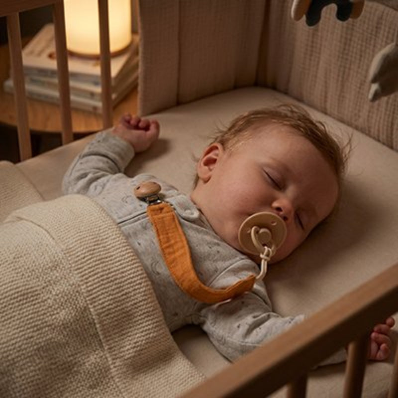 Attache tétine orange bébé dort confortablement 