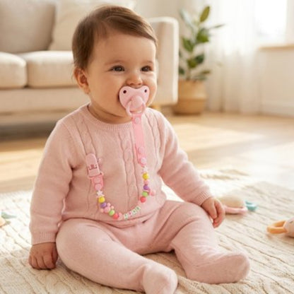 Attache tetine  rose bébé assis sur le tapis