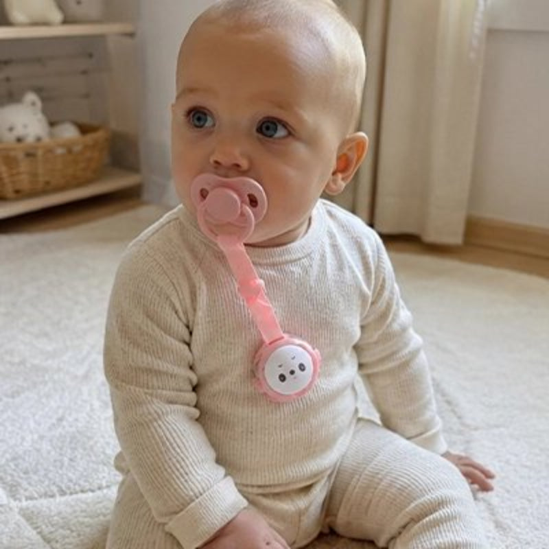 Attache tetine rose, bébé regarde face à la camera