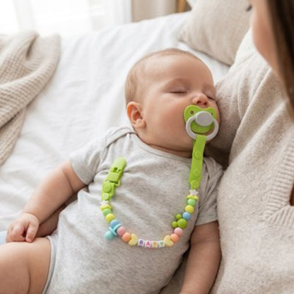 Attache tetine vert bébé qui dort dans les bras de sa maman