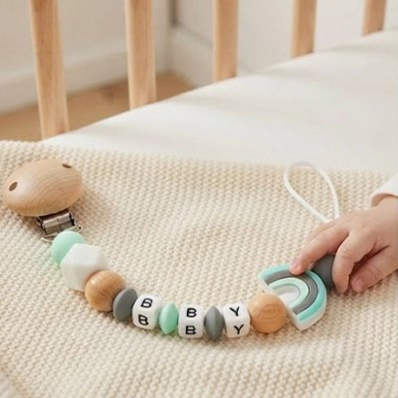 Attache tetine vert sur posé sur le lit de bébé