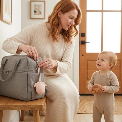 Boite a tetine​ bebe rose bebe regarde sa maman accrocher la boite sur le sac