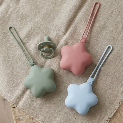 Boite a tetine vert, rose et bleu posées sur une écharpe