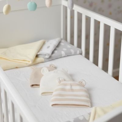 Bonnet bébé abricot,  sur le lit