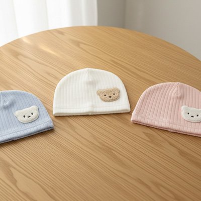 Bonnet bébé naissance bleu,blanc,rose posés sur la table