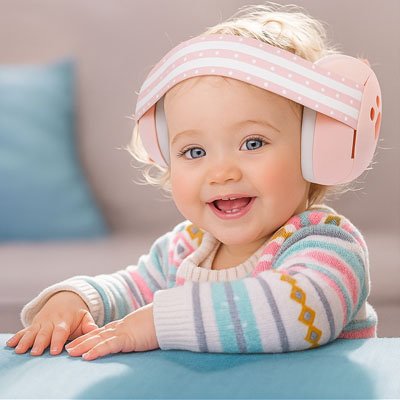 Casque anti bruit bébé  rose bébé assis à table tout souriant