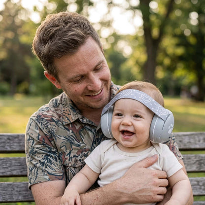 Casque anti bruit pour bébé gris papa qui est assis  sur un banc au parc avec son enfant