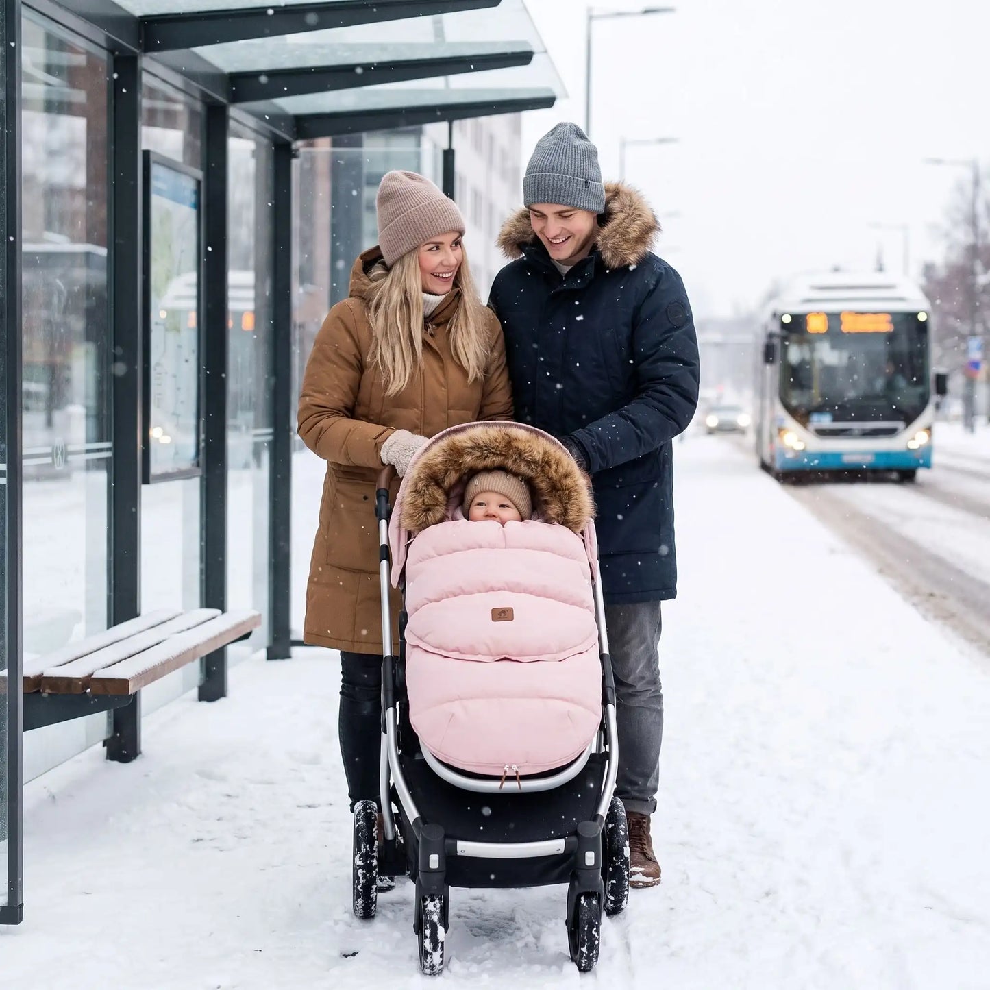chanceliere poussette bebe rose, maman et papa à l'arrêt bus avec bébé bien au chaud
