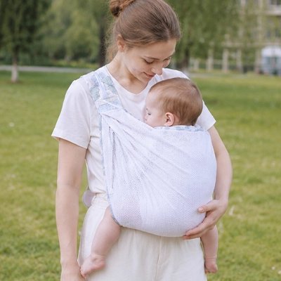 Echarpe de portage blanc, maman au parc avec son bébé qui dort 