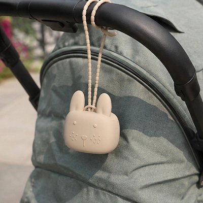 La boite a tetine​ beige attachée sur la poussette