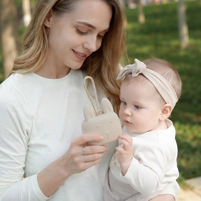 La boite a tetine​ beige que maman montre à son bébé