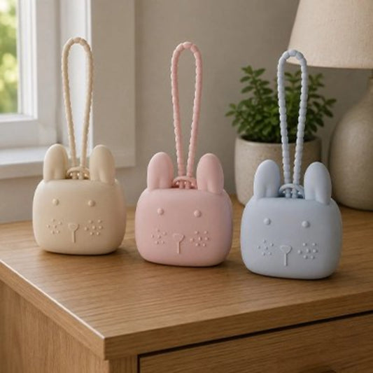 La boite a tetine​ beige, rose et bleu posées sur la table