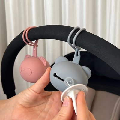  la boite a tetine​ rose et bleu attachées sur la poussette
