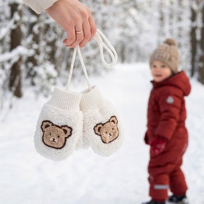 Moufle bébé blanc, l'enfant regarde ses mitaines