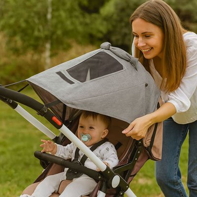 Par soleil pour poussette​ gris bébé assis dans sa poussette avec sa tétine dans la bouche