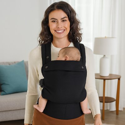 Porte bébé physiologique noir, Bébé dort tranquillement contre sa maman debout au salon