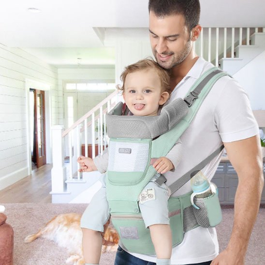 Porte bebe vert, papa porte confortablement bébé assis face vers l'avant
