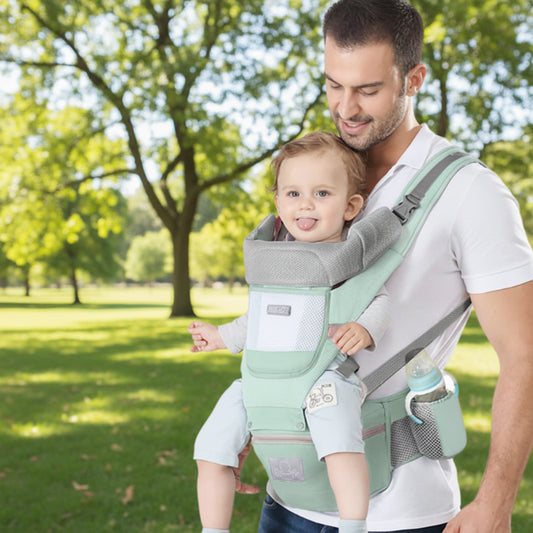 Porte bebe vert, papa porte confortablement bébé assis face vers l'avant au parc