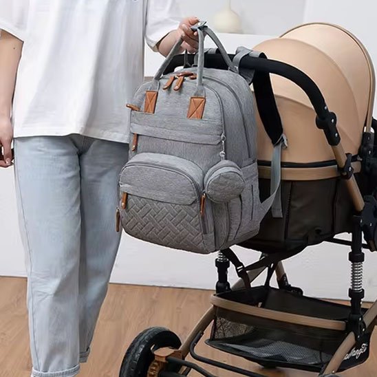 Sac à dos à langer gris accroché sur une poussette