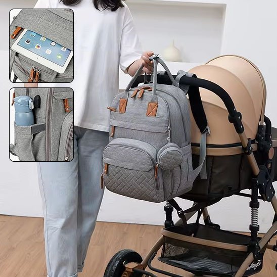 Sac à dos à  langer gris contenant un laptop et une bouteuille d'eau