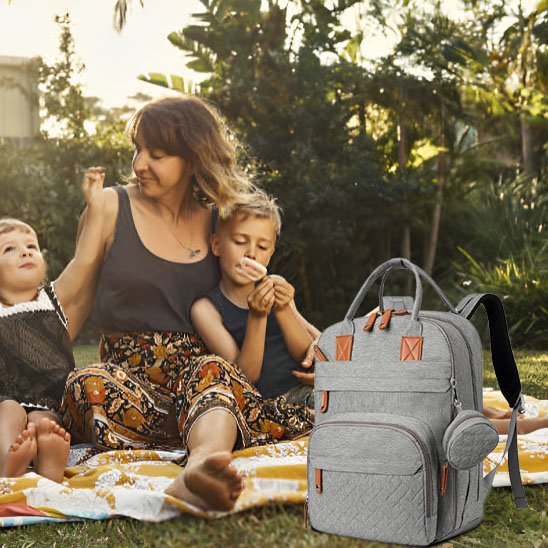 Sac à dos à langer gris, deux enfants assis au parc avec leur maman