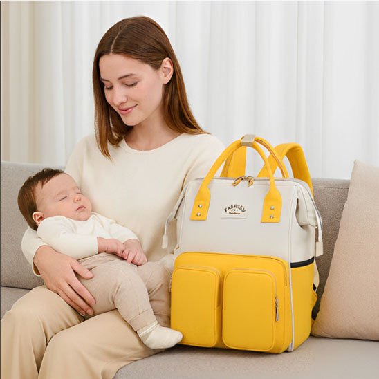 Sac à dos à langer jaune, maman assise sur le sofa avec bébé