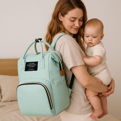 sac a dos a langer vert, bébé en sécurité dans les bras de sa maman
