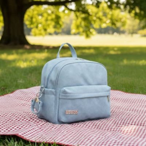 Sac a langer a dos bleu posé sur un tissu sur le gazon