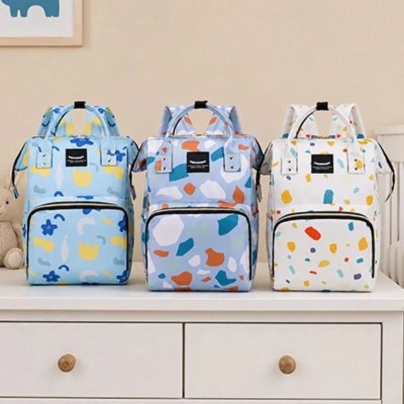 Sac a langer bebe bleu clair, bleu foncé et blanc posés sur la table