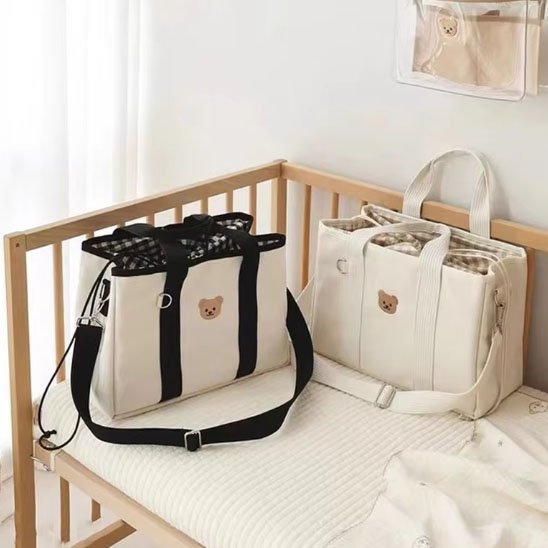 Sac à langer blanc , blanc noir posés sur le lit du bébé