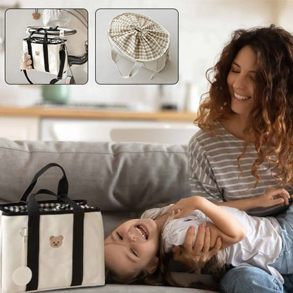 Sac à langer blanc noir posé sur le sofa avec maman qui joue avec sa fille