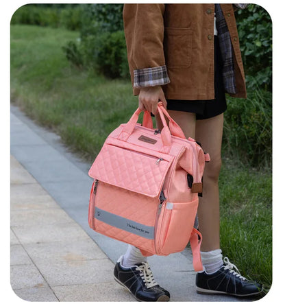 sac à langer sac à dos rose, dans la main d'une madame dans la rue