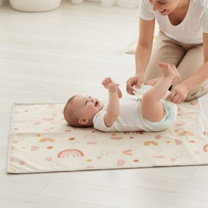 Tapis à langer nomade arc- en - ciel bébé tout souriant avec ses pieds en l'air avec sa maman