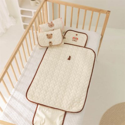 Tapis à langer nomade brun bien étalé sur le lit