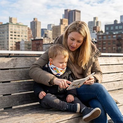 Tour de cou blanc/dinosaure, maman assise sur un banc en ville avec son fils